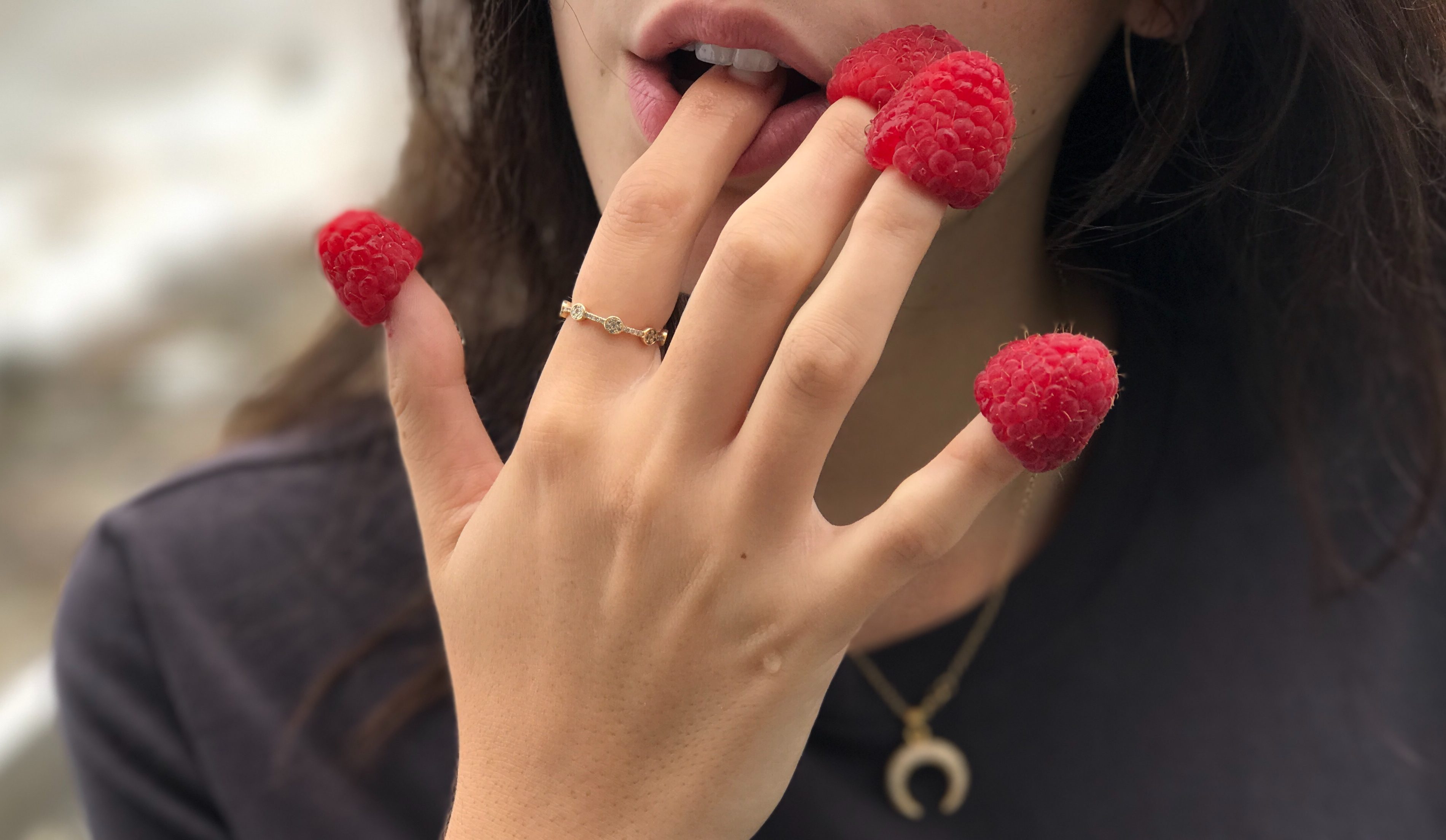 Girl with raspberries on fingers.